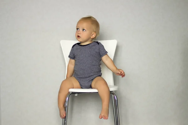 Tankeväckande pojke sitter på en stol ioch tittar bort — Stockfoto