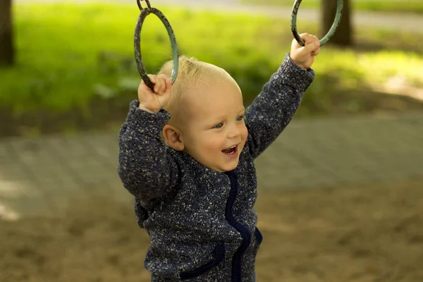 Милый мальчик занимается спортом в парке. Забавные детские тренировки на атлетических кольцах — стоковое фото