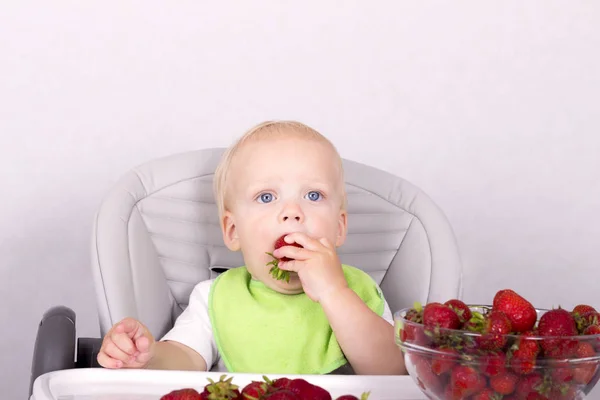 Милый малыш, поедающий клубнику. Смешной мальчик с клубникой в руке — стоковое фото