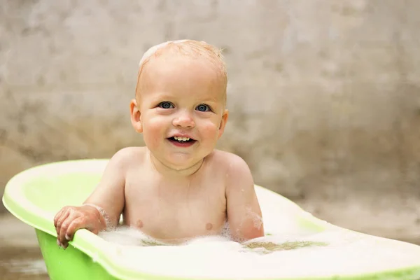 Uśmiechający się maluch biorąc kąpiel z pianką mydło na jego włosy na szarym tle — Zdjęcie stockowe