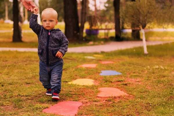Задумчивый малыш гуляет по осеннему парку и держит руку отца — стоковое фото