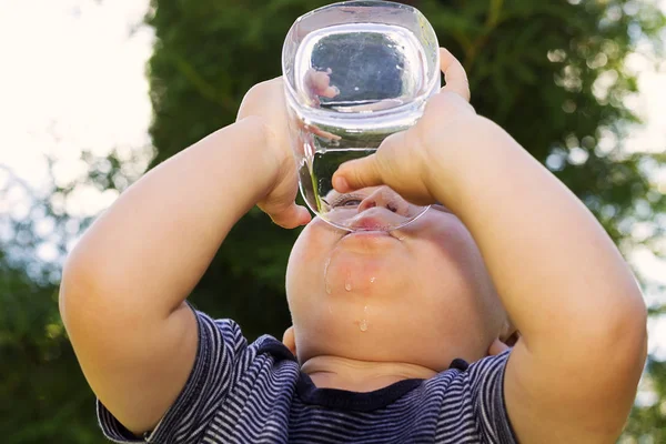 Fantastico bambino che beve acqua dal bicchiere. Ritratto di chiusura. Colpo esterno — Foto Stock