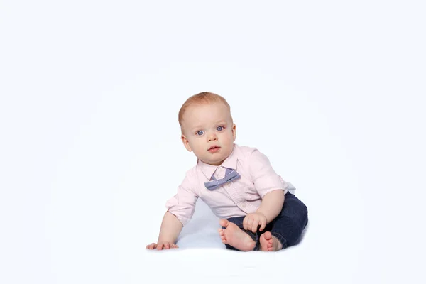 Söt spädbarn pojke i en rosa skjorta och en fluga sitter på den vita bakgrunden och tittar på kameran. Kopiera utrymme — Stockfoto
