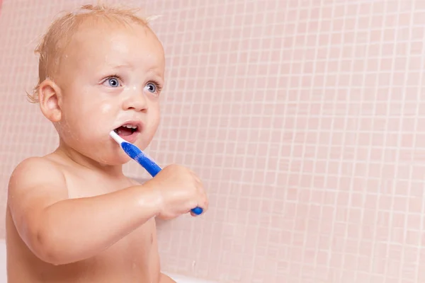 Милий малюк з відкритими очима приймає ванну і чистить зуби. Копіювати простір — стокове фото