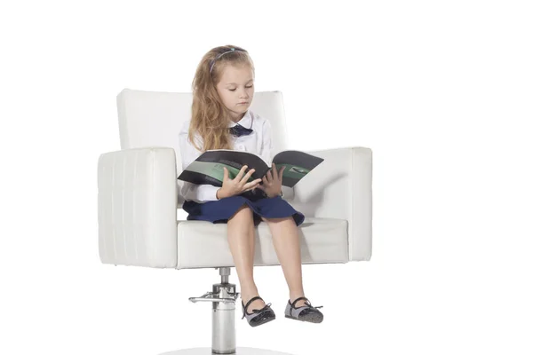 7 anni ragazza seduta su una sedia e la lettura isolata su sfondo bianco — Foto Stock