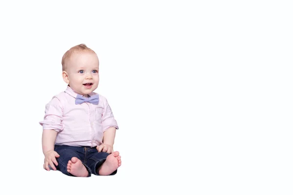 Menino bonito em uma camisa rosa e um laço sentado no fundo branco e olhando para a câmera. Espaço de cópia — Fotografia de Stock