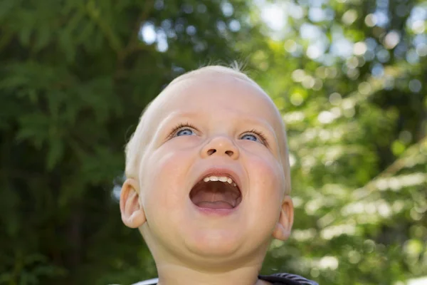 Close-up portrait of cute smiling one year toddler against green nature background. adorable baby boy looking up and smiling — Stock Photo, Image