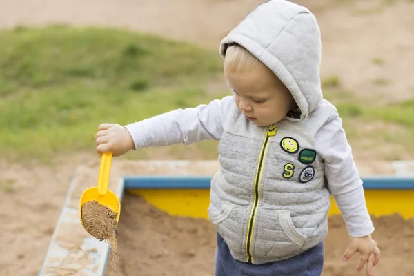 Милый мальчик играет на песке на детской площадке — стоковое фото