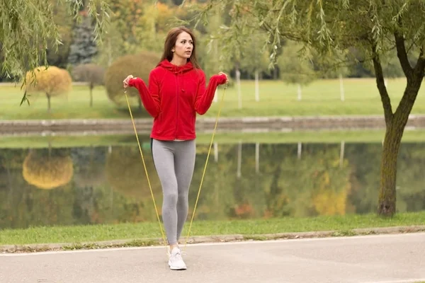 Tiro ao ar livre de jovem mulher focada com corda de salto ao ar livre na natureza. Fitness feminino exercitando com corda de salto em um parque em um dia ensolarado . — Fotografia de Stock