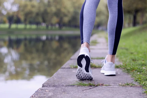 Uma mulher desportiva a correr na margem do rio. Fitness e conceito de bem-estar de treino . — Fotografia de Stock