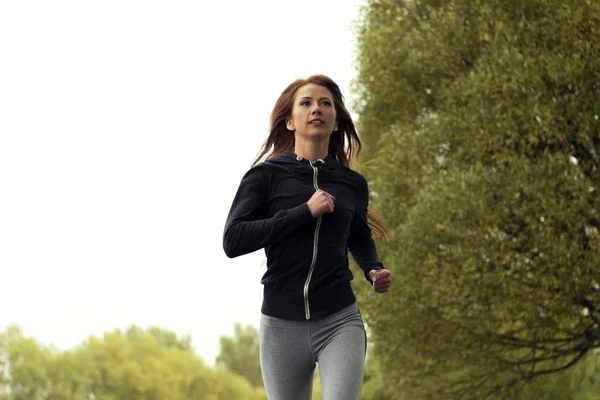 Joven mujer feliz corriendo en el parque de otoño. Correr Chica Fitness — Foto de Stock