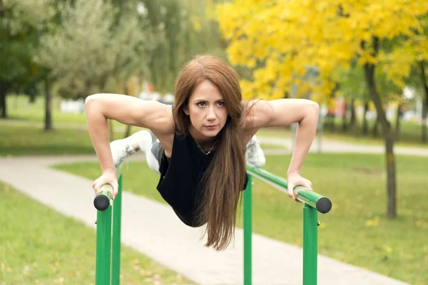 Linda atleta feminina se exercitando em barras paralelas, fazendo flexões — Fotografia de Stock