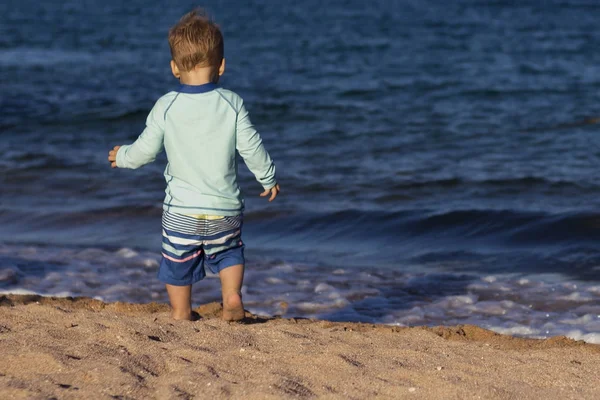 幼儿在游泳服上的背部视图跑到海边。复制空间 — 图库照片