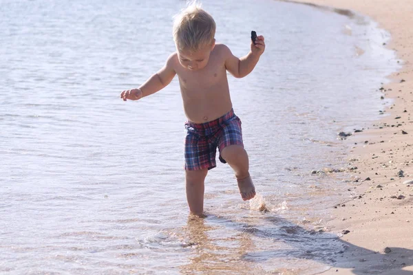 Bébé drôle courant dans la mer. Bébé garçon mignon s'amuse en vacances — Photo