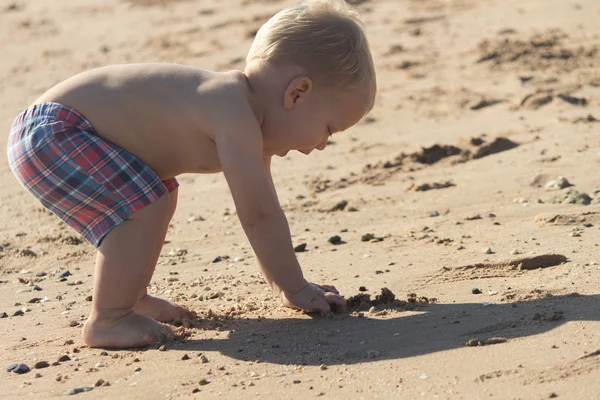 Αστείο, μικρό παιδί παίζει με την άμμο στην παραλία. Χαριτωμένο μωρό αγόρι έχει τη διασκέδαση στις διακοπές — Φωτογραφία Αρχείου