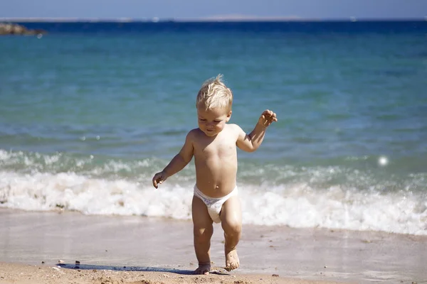 Gelukkig kind, schattige blonde peuter jongen in luier, spelen op het strand lopen in het water, genieten van de Oceaan op een zonnige zomerdag — Stockfoto