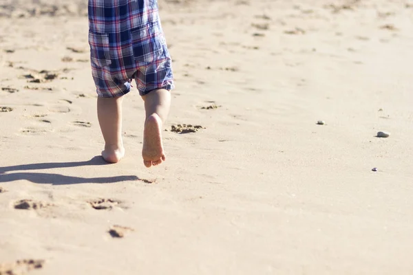 儿童双腿站在沙滩上。宝宝脚在沙子里。夏季海滩背景。夏季假日概念。复制空间 — 图库照片