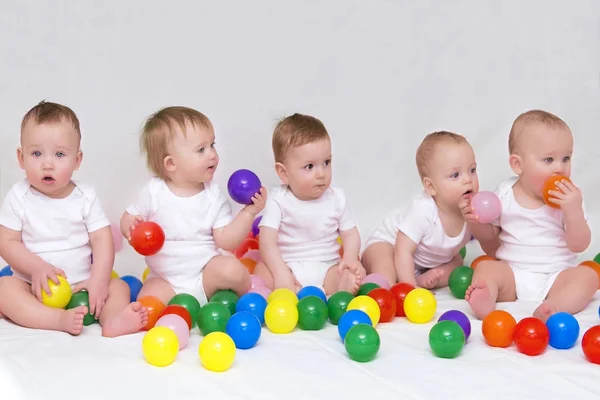 Портрет пяти милых младенцев на светлом фоне, играющих с красочными шариками — стоковое фото