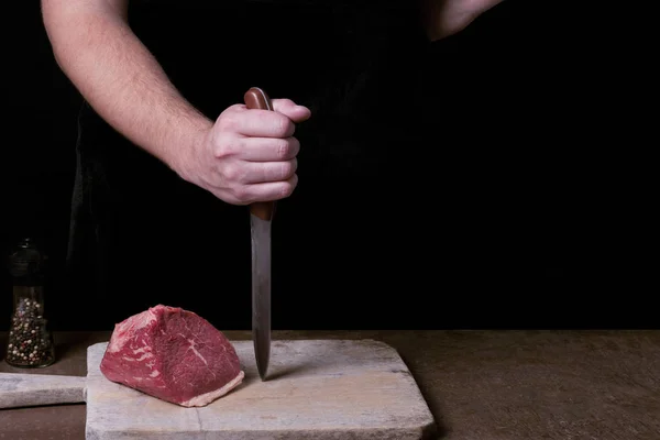 Macellaio che si prepara a tagliare carne di faggio cruda sulla cucina. Copia spazio — Foto Stock