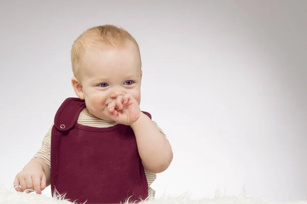 Härlig liten pojke ler, sitter på vit filt, studio skott, isolerade på grå bakgrund, funny baby porträtt — Stockfoto