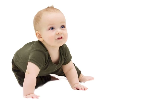 Bedårande spädbarn pojke sitter på det vita täcket och tittar — Stockfoto