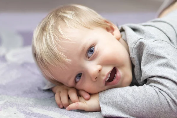Glada barnet om på sängen och titta på kameran — Stockfoto