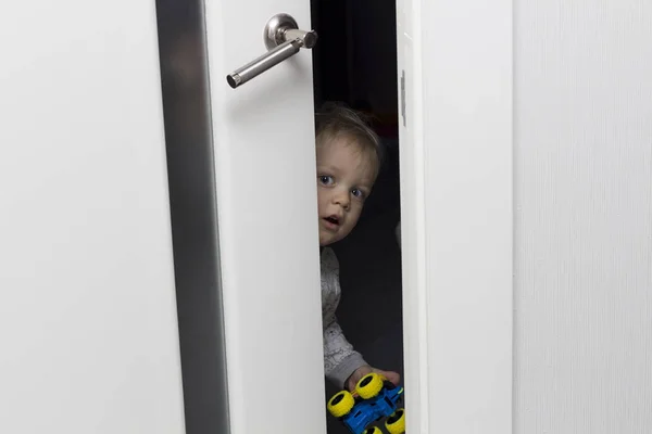 Criança bonito olhando para fora de trás da porta ajar — Fotografia de Stock