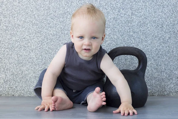 Sport jest życie. Szczęśliwy uśmiechający się maluch siedząc na podłodze z kettlebell. — Zdjęcie stockowe