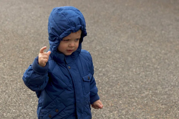 Little boy in a blue jacket with a hood on the children playground. Copy space — Stock Photo, Image