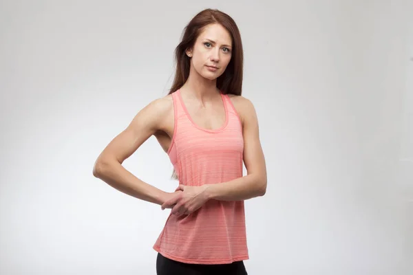 Linda mujer joven en ropa deportiva sonriendo. Modelo de fitness muscular sobre fondo gris — Foto de Stock