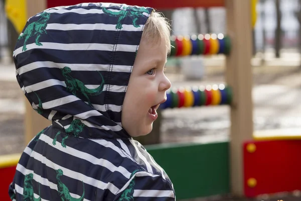 Портрет улыбающегося мальчика, играющего на детской площадке, Верхнего мальчика в капюшоне, играющего на открытом воздухе — стоковое фото
