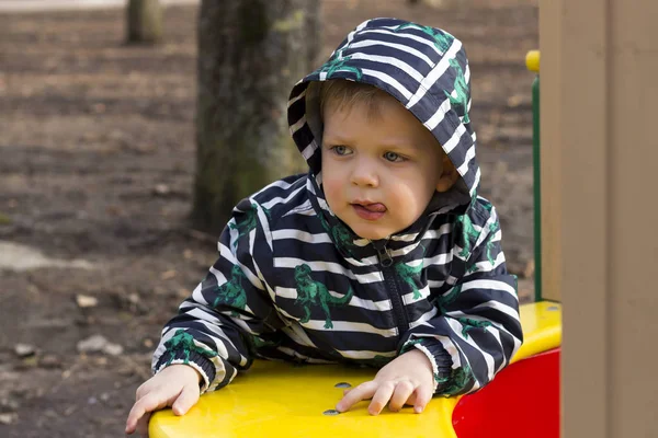 Portret zadumany mały chłopiec gry na zewnątrz na placu zabaw, śliczny maluch w kaptur, bawiąc się na zewnątrz. — Zdjęcie stockowe