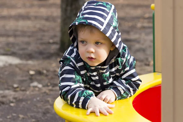 Portret van doordachte jongetje buiten spelen in de Speeltuin, schattig peuter in een kap die buiten spelen. — Stockfoto