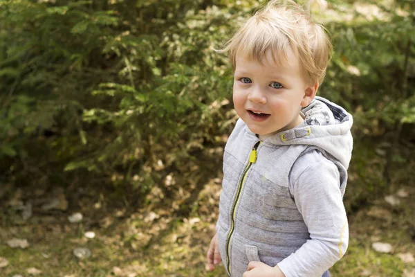 Vackra lilla blonda hår pojke med öppen mun, glada ögon i skogen våren. Barnporträtt. Kreativa koncept. Sommartid. Närbild — Stockfoto