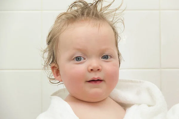 Retrato de cerca de un divertido niño caucásico de ojos azules rizados en una toalla blanca después de una ducha sobre un fondo blanco —  Fotos de Stock