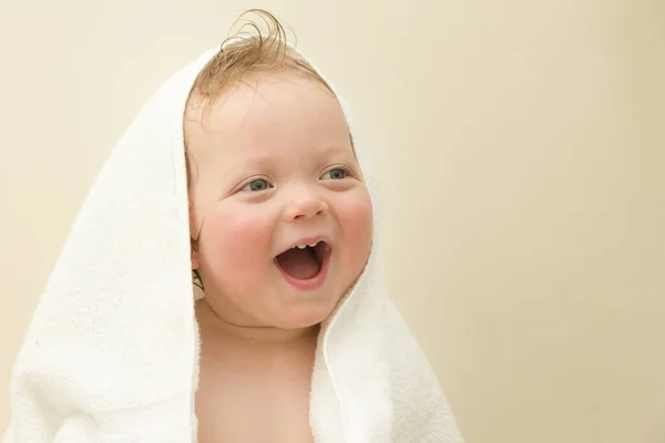 Retrato de um menino bonito de olhos azuis rindo caucasiano em uma toalha branca depois de um banho em um fundo branco. Espaço de cópia — Fotografia de Stock