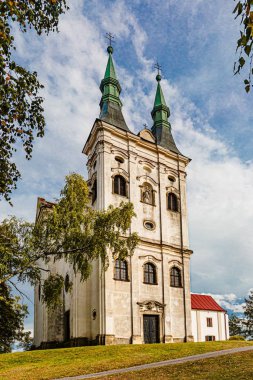 Krahulci / Çek Cumhuriyeti - 27 Eylül 2019: Nepomuk Kilisesi, güneşli bir günde mavi gökyüzü ve bulutlarla yeşil bir tepenin üzerinde duran 18. yüzyıldan kalma beyaz bir bina. 