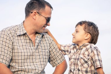 Baba ve oğul gündüz vakti sahada oynuyorlar. İnsanlar dışarıda eğleniyor. Arkadaş canlısı aile kavramı.