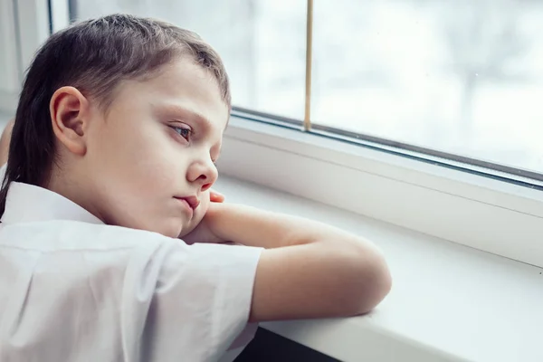 一个悲伤的小男孩坐在窗边 悲伤的概念 — 图库照片
