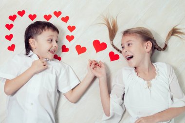 Küçük bir çocuk ve kız yerde yatıyor. Sevgililer Günü 'nün ve Kardeşlerin Sonsuza Kadar Birlikte Olması kavramı