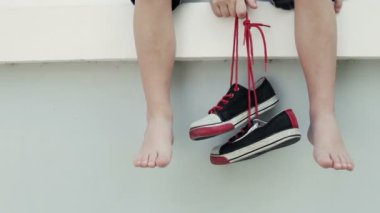 Evin oturan ve gençlik spor ayakkabıları gün anda onun elinde tutmak küçük çocuk.
