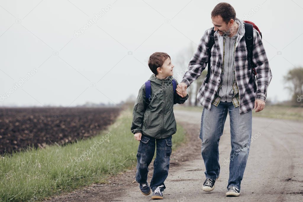 Father and son walking on the road at the day time.  Concept of friendly family.
