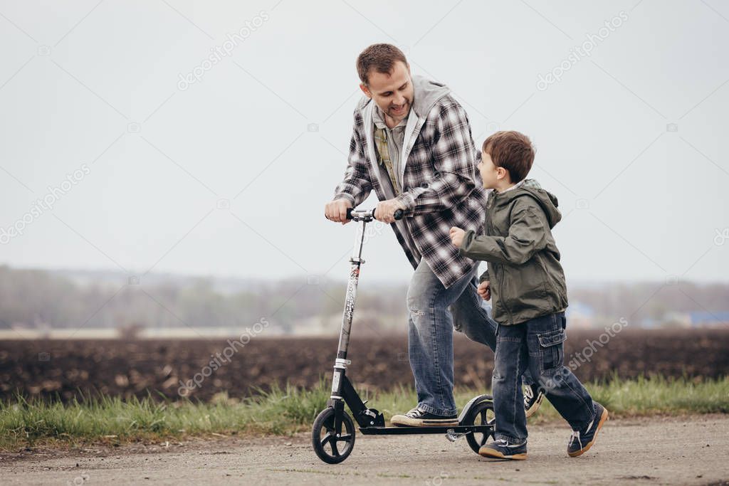 Father and son playing on the road at the day time. People having fun outdoors. Concept of friendly family.