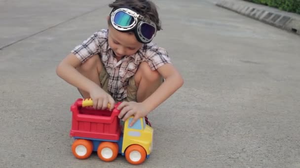 快乐的小男孩在路上玩着玩具车 快乐青春的概念 — 图库视频影像