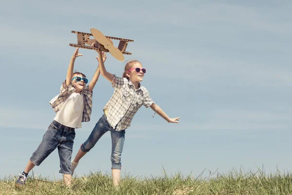 两个小孩白天在公园里玩纸板玩具飞机 快乐游戏的概念 孩子们在外面玩得很开心在蓝天的背景上拍摄的图片 — 图库照片