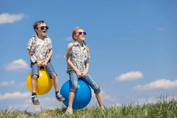 兄と妹のフィールドでは その日のプレー 子供たちは屋外で楽しんでいます 彼らは芝生の上で膨脹可能なボールに飛び乗る 友好的な家族の概念 — ストック写真