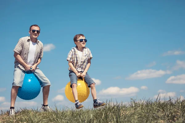 父子俩白天在田里玩耍 人们在户外玩得很开心他们在草坪上跳着充气球 友好家庭的概念 — 图库照片