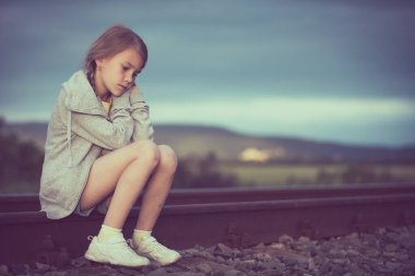 Gündüz vakti demiryolunda oturan üzgün genç bir kızın portresi. Üzüntü kavramı.
