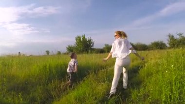 Anne ve oğlu gündüz vakti parkta oynuyorlar. İnsanlar sahada eğleniyor. Arkadaş canlısı aile kavramı ve yaz tatili.