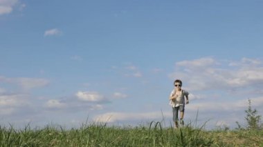 Küçük çocuk gündüz vakti sahada oynuyor. Çocuk dışarıda eğleniyor. Çimlerde koşuyor..